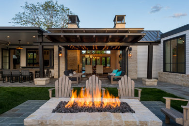 Example of a classic backyard patio design with a fire pit and a roof extension