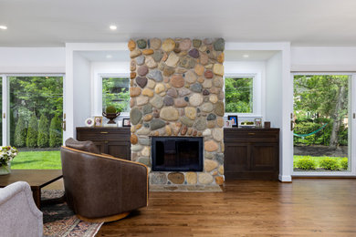 Large transitional open concept medium tone wood floor and brown floor living room photo in Detroit with white walls, a standard fireplace and a stone fireplace