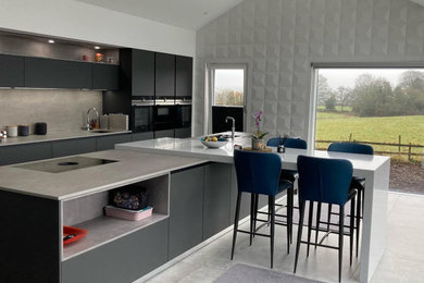 This is an example of a large modern single-wall kitchen/diner in Other with a submerged sink, flat-panel cabinets, grey cabinets, quartz worktops, grey splashback, engineered quartz splashback, black appliances, slate flooring, an island, grey floors and grey worktops.