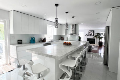 Kitchen - large modern porcelain tile and white floor kitchen idea in New York with an undermount sink, white cabinets, quartz countertops, white backsplash, stainless steel appliances, an island and white countertops
