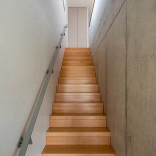 Cette image montre un grand escalier droit minimaliste avec des marches en bois, des contremarches en bois et un garde-corps en matériaux mixtes.