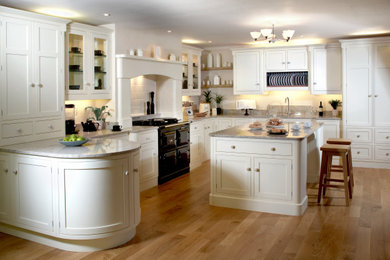 Inspiration for a large traditional u-shaped enclosed kitchen in Other with shaker cabinets, white splashback, medium hardwood flooring, an island, brown floors, a chimney breast, a submerged sink, white cabinets, granite worktops, porcelain splashback, black appliances and beige worktops.