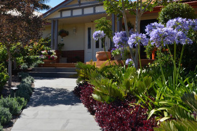 Photo of a small mediterranean front yard full sun xeriscape for spring in Perth with a garden path and natural stone pavers.