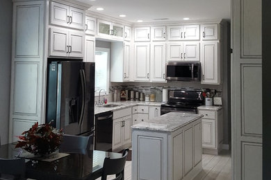Inspiration for a mid-sized transitional l-shaped porcelain tile and beige floor eat-in kitchen remodel in Chicago with an undermount sink, raised-panel cabinets, white cabinets, granite countertops, multicolored backsplash, matchstick tile backsplash, stainless steel appliances and an island