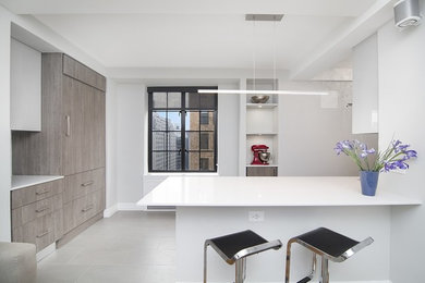 Design ideas for a mid-sized contemporary galley separate kitchen in New York with an undermount sink, flat-panel cabinets, grey cabinets, quartz benchtops, white splashback, glass tile splashback, panelled appliances, porcelain floors, no island, grey floor and white benchtop.