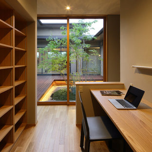 This is an example of a world-inspired home office and library in Other with brown walls, medium hardwood flooring, a built-in desk and brown floors.