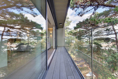 This is an example of a large contemporary apartment glass railing balcony in Dorset.