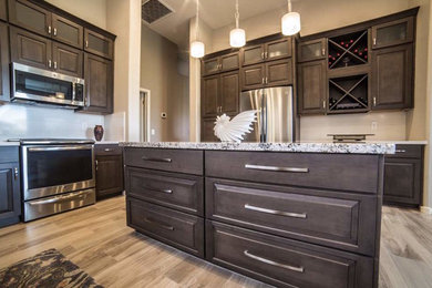 Eat-in kitchen - traditional l-shaped light wood floor eat-in kitchen idea in Phoenix with an undermount sink, raised-panel cabinets, medium tone wood cabinets, granite countertops, white backsplash, ceramic backsplash, stainless steel appliances and an island
