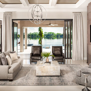 Großes, Offenes Mediterranes Wohnzimmer mit beiger Wandfarbe, Kalkstein, beigem Boden, Gaskamin, Kaminsims aus Metall und Wand-TV in Orlando