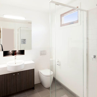 メルボルンのコンテンポラリースタイルのおしゃれな浴室 (中間色木目調キャビネット、コーナー設置型シャワー、壁掛け式トイレ、白いタイル、磁器タイル、白い壁、磁器タイルの床) の写真