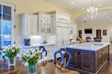 Example of a large classic galley medium tone wood floor eat-in kitchen design in Phoenix with beaded inset cabinets, medium tone wood cabinets, marble countertops, an island, a double-bowl sink, white backsplash, subway tile backsplash and stainless steel appliances