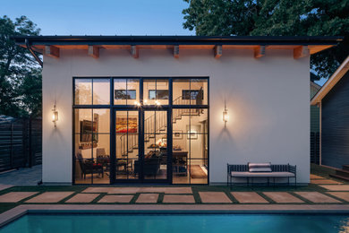 Small transitional white two-story stucco tiny house photo in Austin with a shed roof, a metal roof and a black roof