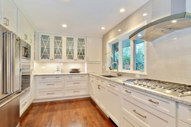 Inspiration for a mid-sized transitional u-shaped medium tone wood floor and brown floor open concept kitchen remodel in Salt Lake City with an undermount sink, shaker cabinets, white cabinets, granite countertops, gray backsplash, subway tile backsplash, stainless steel appliances, a peninsula and gray countertops
