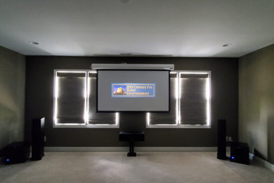 Ejemplo de cine en casa tradicional con moqueta y pantalla de proyección