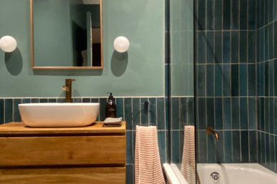 ロンドンにあるお手頃価格の小さなモダンスタイルのおしゃれな子供用バスルーム (フラットパネル扉のキャビネット、中間色木目調キャビネット、ドロップイン型浴槽、青いタイル、セラミックタイル、磁器タイルの床、洗面台1つ、フローティング洗面台) の写真
