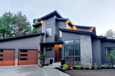 Large modern black two-story mixed siding and board and batten house exterior idea in Grand Rapids