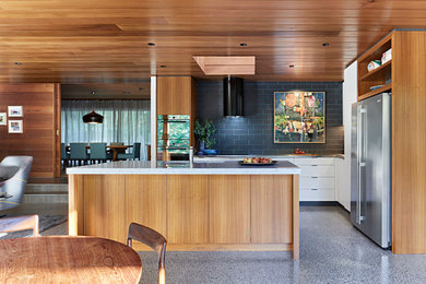 Photo of a mid-sized midcentury l-shaped eat-in kitchen in Melbourne with an undermount sink, flat-panel cabinets, medium wood cabinets, marble benchtops, black splashback, porcelain splashback, concrete floors, with island, grey floor, stainless steel appliances and grey benchtop.