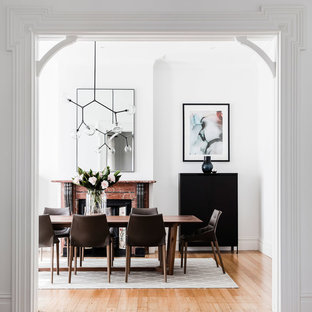 Contemporary separate dining room in Sydney with white walls, light hardwood floors, a standard fireplace and a stone fireplace surround.