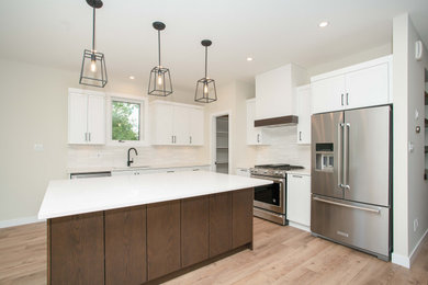 Example of a trendy l-shaped vinyl floor and beige floor eat-in kitchen design in Other with flat-panel cabinets, white cabinets, quartzite countertops, white backsplash, ceramic backsplash, stainless steel appliances, an island and white countertops