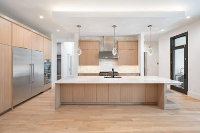 Example of a huge trendy light wood floor, brown floor and tray ceiling kitchen design in Houston with an undermount sink, flat-panel cabinets, light wood cabinets, quartz countertops, white backsplash, porcelain backsplash, stainless steel appliances, an island and white countertops