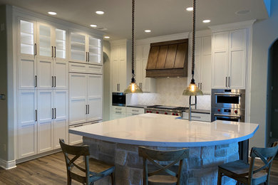 Inspiration for a large coastal l-shaped laminate floor and multicolored floor eat-in kitchen remodel in Houston with a farmhouse sink, shaker cabinets, white cabinets, quartz countertops, multicolored backsplash, ceramic backsplash, stainless steel appliances, an island and multicolored countertops