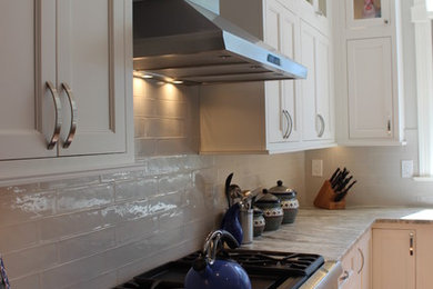 Example of a large transitional l-shaped medium tone wood floor open concept kitchen design in Philadelphia with a farmhouse sink, shaker cabinets, white cabinets, granite countertops, white backsplash, subway tile backsplash, stainless steel appliances and an island