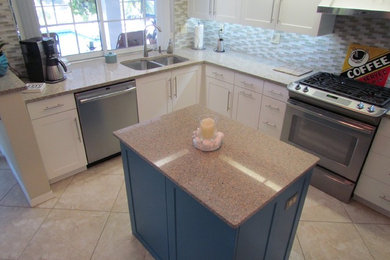 Mid-sized transitional l-shaped ceramic tile and beige floor enclosed kitchen photo in Tampa with a double-bowl sink, shaker cabinets, white cabinets, granite countertops, multicolored backsplash, mosaic tile backsplash, stainless steel appliances and an island