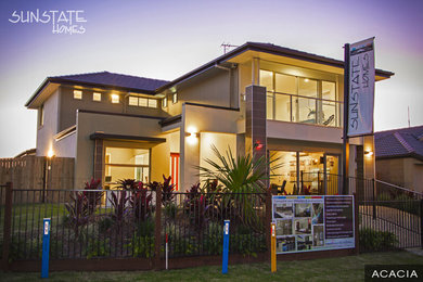 Large contemporary two-storey stucco beige house exterior in Brisbane with a hip roof and a tile roof.