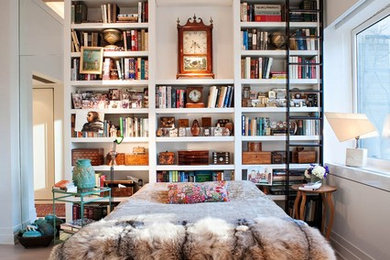 This is an example of an eclectic bedroom in New York with white walls, light hardwood floors and no fireplace.