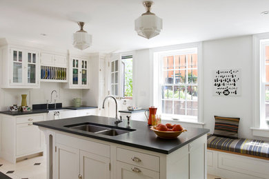 This is an example of a mid-sized traditional u-shaped separate kitchen in New York with glass-front cabinets, white cabinets, soapstone benchtops, white splashback, with island, a double-bowl sink, stainless steel appliances and limestone floors.