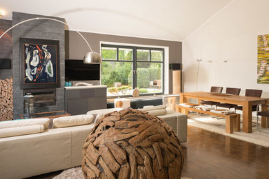 Geräumige, Offene Moderne Bibliothek mit grauer Wandfarbe, dunklem Holzboden, Kamin, Kaminumrandung aus Stein, braunem Boden und TV-Wand in Hamburg