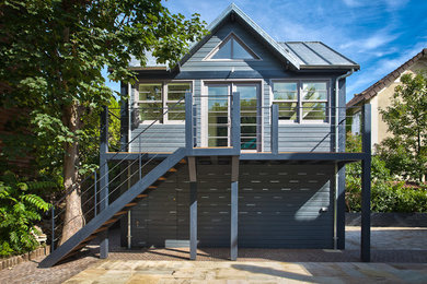 Cette photo montre une façade de maison grise tendance en bois à un étage avec un toit à deux pans.