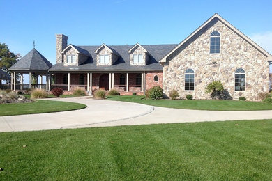Large eclectic brown two-story stone exterior home photo in Other