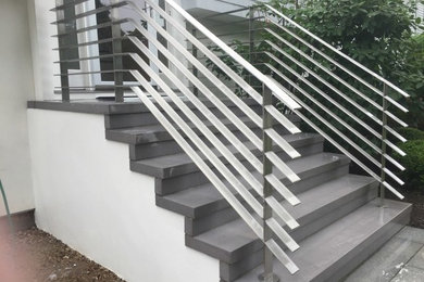 Imagen de escalera recta moderna de tamaño medio con escalones de pizarra, contrahuellas de pizarra y barandilla de metal