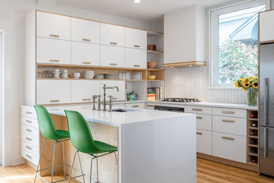 Eat-in kitchen - small contemporary u-shaped light wood floor eat-in kitchen idea in Ottawa with an undermount sink, flat-panel cabinets, white cabinets, quartzite countertops, white backsplash, ceramic backsplash and stainless steel appliances