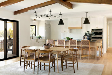 Example of a transitional medium tone wood floor, brown floor, exposed beam and vaulted ceiling kitchen/dining room combo design in Minneapolis with white walls