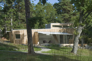 This is an example of a large contemporary two-storey house exterior in Stockholm with wood siding, a flat roof and a metal roof.