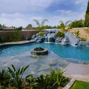 Bild på en stor funkis anpassad baddamm på baksidan av huset, med vattenrutschkana och naturstensplattor