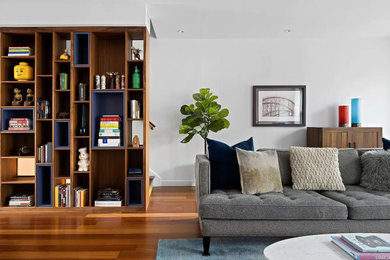 Example of a mid-sized minimalist loft-style medium tone wood floor and brown floor living room library design in New York with white walls, a standard fireplace, a tile fireplace and no tv