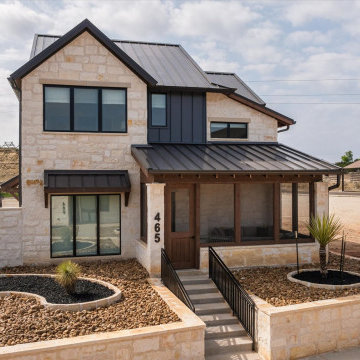 Striking modern ranch exterior with limestone façade, black metal roof, and a we