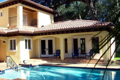 This is an example of a mid-sized traditional backyard rectangular lap pool in Tampa with a hot tub and concrete pavers.