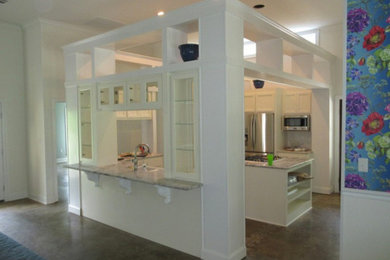 Example of a medium tone wood floor kitchen design in New Orleans with white cabinets, stainless steel appliances and an island
