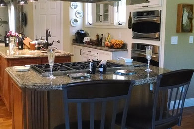 Large elegant u-shaped medium tone wood floor open concept kitchen photo in San Francisco with a farmhouse sink, recessed-panel cabinets, white cabinets, granite countertops, white backsplash, mosaic tile backsplash, stainless steel appliances and an island