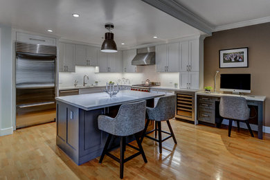 This is an example of a mid-sized transitional l-shaped kitchen pantry in San Francisco with an undermount sink, recessed-panel cabinets, white cabinets, quartz benchtops, white splashback, ceramic splashback, stainless steel appliances, light hardwood floors and with island.