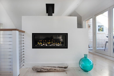 Photo of a mid-sized beach style loft-style family room in Portland Maine with white walls, light hardwood floors, a standard fireplace and a plaster fireplace surround.