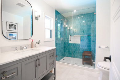 Mid-sized trendy master porcelain tile, white floor and single-sink alcove shower photo in Los Angeles with shaker cabinets, gray cabinets, white walls, an undermount sink, quartz countertops, a hinged shower door, white countertops, a niche and a freestanding vanity