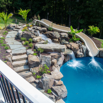 Custom pool with rock waterfalls, water slide & swim up pool bar.