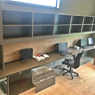 Photo of a large modern study in Vancouver with brown walls, carpet, a built-in desk and beige floors.