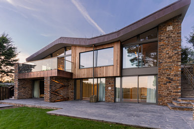 Diseño de fachada de casa contemporánea grande de dos plantas con revestimiento de madera