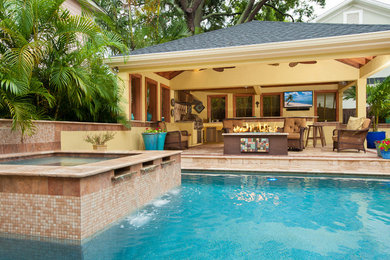 Inspiration for a large contemporary backyard custom-shaped pool in Tampa with a hot tub and natural stone pavers.